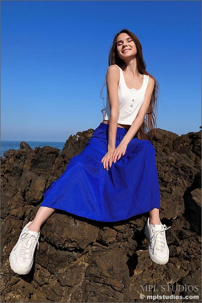 Leona Mia stting on rocks in her blue dress